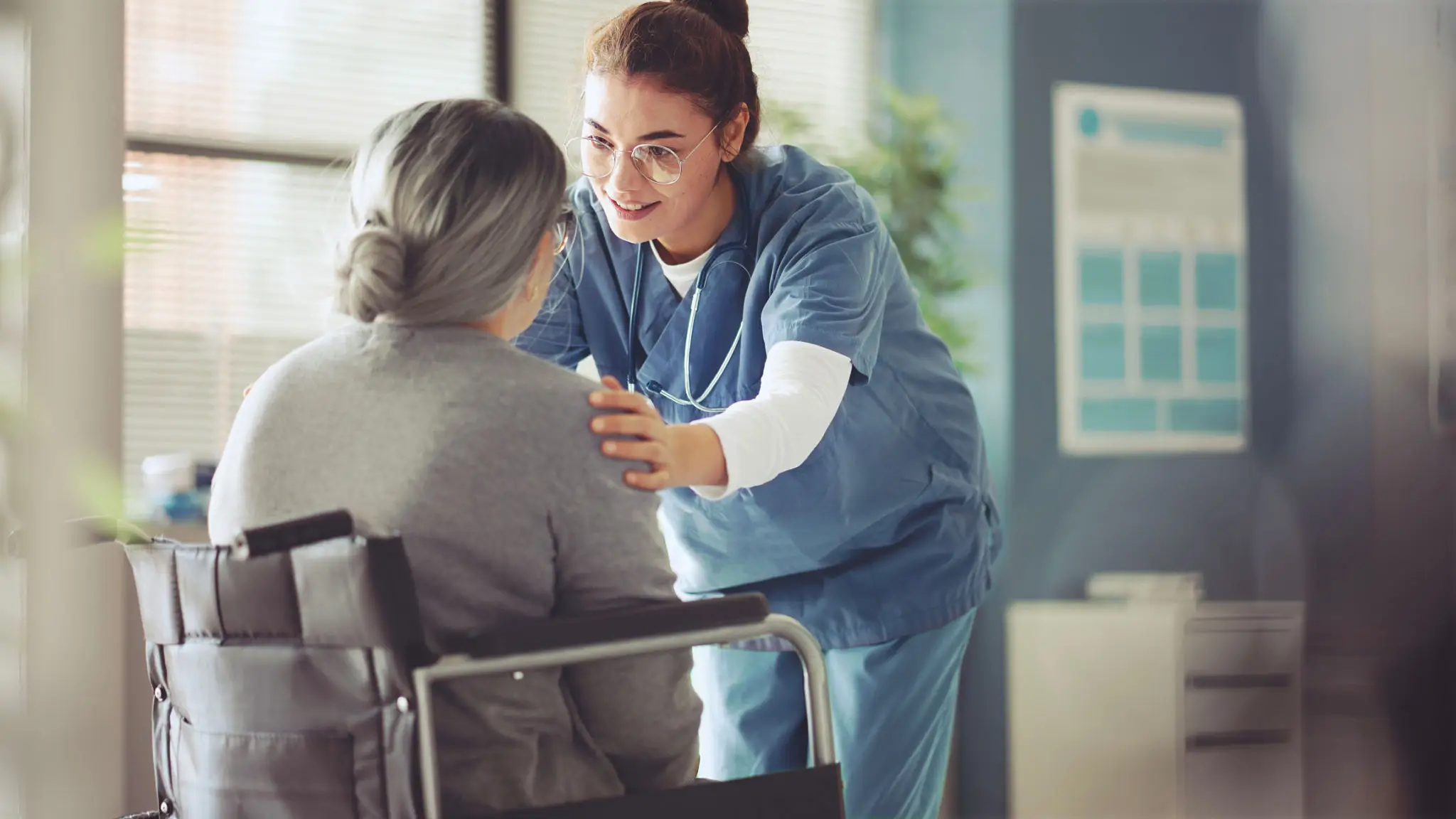 Caregiver supporting elderly patient in clinic