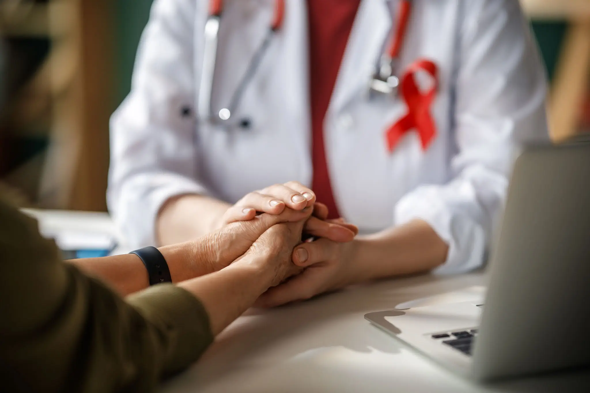 Doctor comforting patient with red ribbon