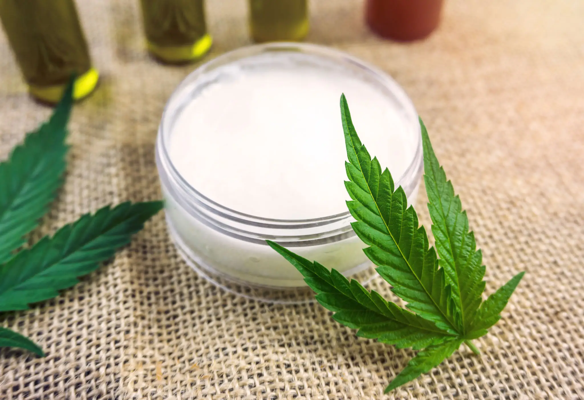 Herbal cream with cannabis leaves on burlap