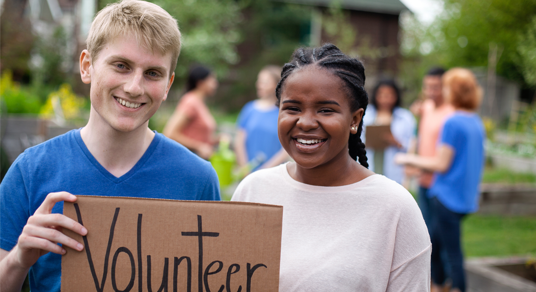 Young adults holding volunteer sign